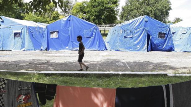 Ein Junge geht an einer Reihe blauer Zelte vorbei, im Vordergrund hängt Wäsche zum Trocknen.