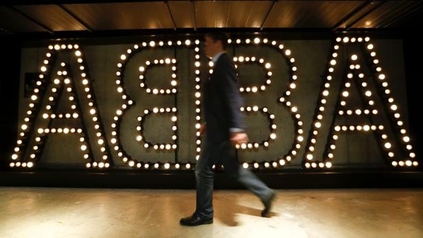 Eine Person geht an einem großen ABBA-Schriftzug aus Glühbirnen vorbei.