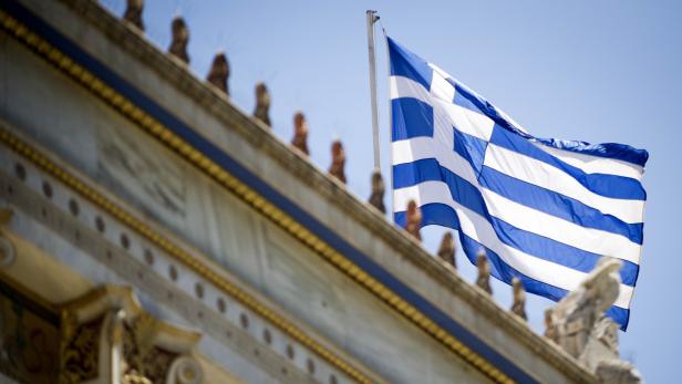 Die griechische Flagge weht vor einem Gebäude mit klassischer Architektur.