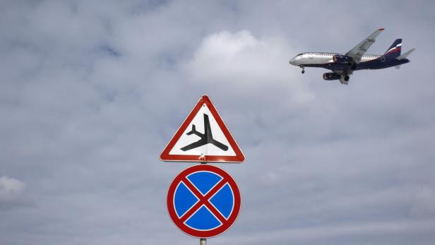 Ein Flugzeug landet im Hintergrund über einem Warnschild für Flugverkehr.