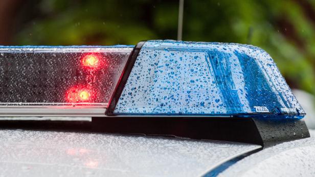 Blaulicht und rote Warnleuchten auf dem Dach eines Einsatzfahrzeugs im Regen.