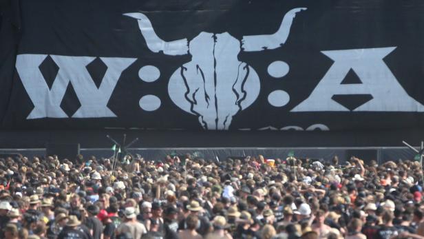 Eine große Menschenmenge vor einer Bühne mit dem Wacken Open Air Logo.