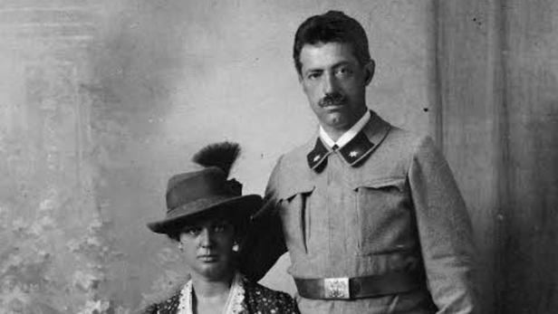 Ein Mann in Uniform und eine Frau mit Hut posieren für ein Schwarzweißfoto.