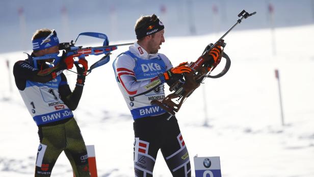 Zwei Biathleten mit Gewehren im Schnee.