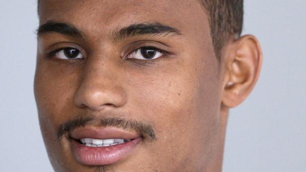 Porträt eines jungen Mannes mit dunklen Haaren und leichtem Bartwuchs.