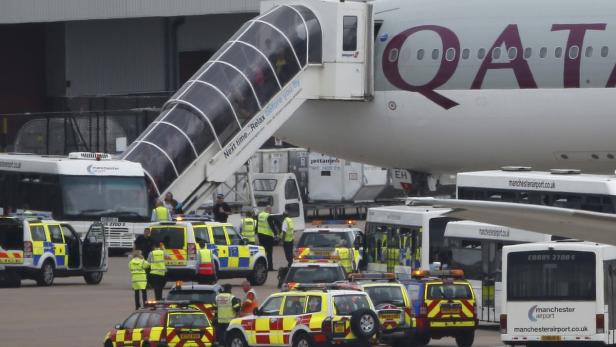 Ein Flugzeug der Qatar Airways steht am Flughafen, umgeben von Sicherheitsfahrzeugen und Bussen.