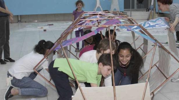 Kopie von Kopie von Romano ButiQ Kinder besteigen die fahrbare zuvor selbst gebaute Rakete im Atrium des Wien Museums.