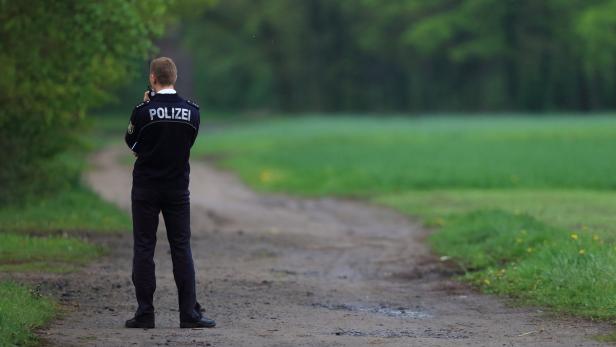 Ein Polizist steht auf einem Feldweg und blickt in die Ferne.