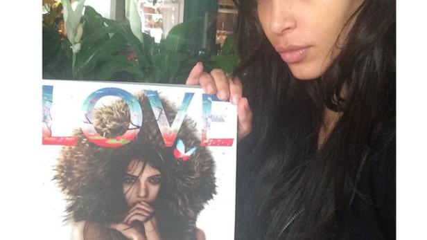 Kim Kardashian hält eine Ausgabe des „Love“-Magazins mit Kendall Jenner auf dem Cover.