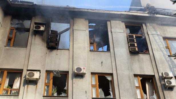 Ein Gebäude mit Brandschäden und zerbrochenen Fenstern wird mit einem Wasserwerfer gelöscht.