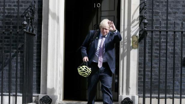 Boris Johnson verlässt 10 Downing Street mit einem Fahrradhelm in der Hand.