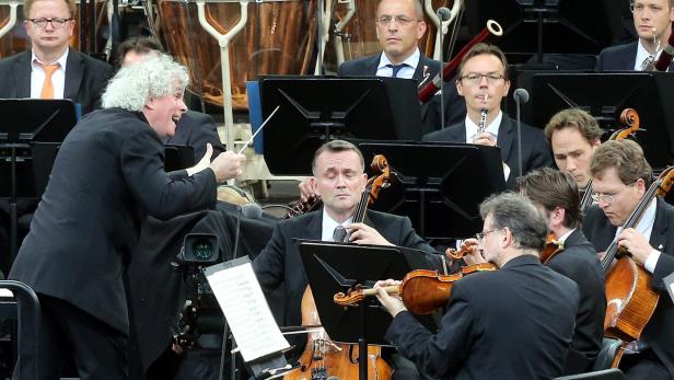 Ein Dirigent leitet ein Orchester mit Streichern und Bläsern.