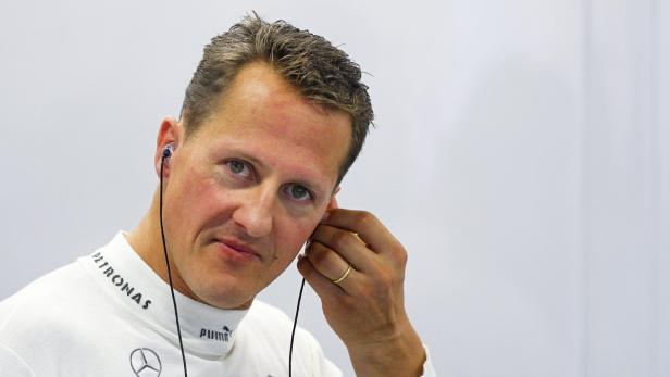 Michael Schumacher mit Kopfhörern vor einem weißen Hintergrund.