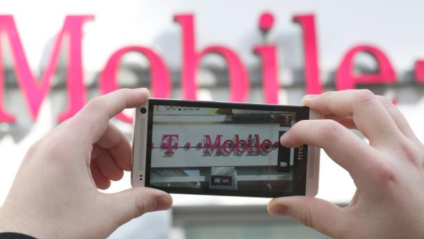 Eine Person fotografiert mit einem Smartphone das T-Mobile-Logo.