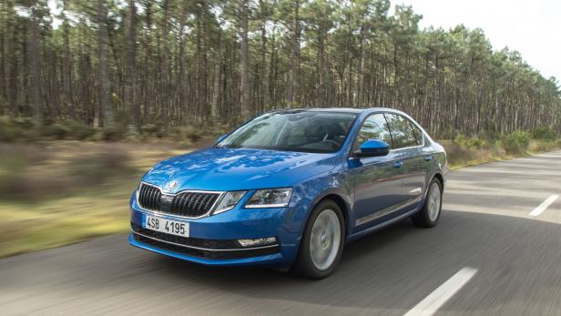 Ein blauer Škoda Octavia fährt auf einer Landstraße an einem Wald vorbei.