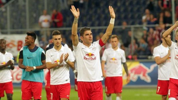 Eine Gruppe Fußballspieler in weißen und roten Trikots jubelt.
