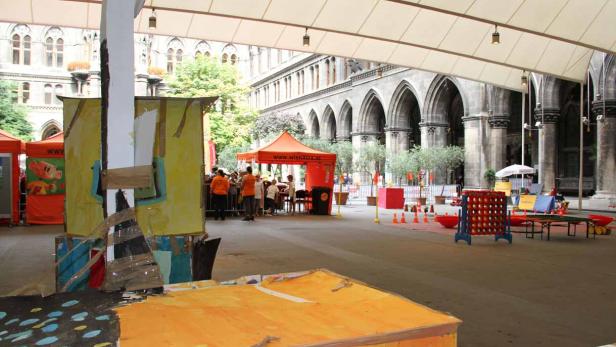 Eine Veranstaltung mit Spielständen und Imbissständen vor einem historischen Gebäude.