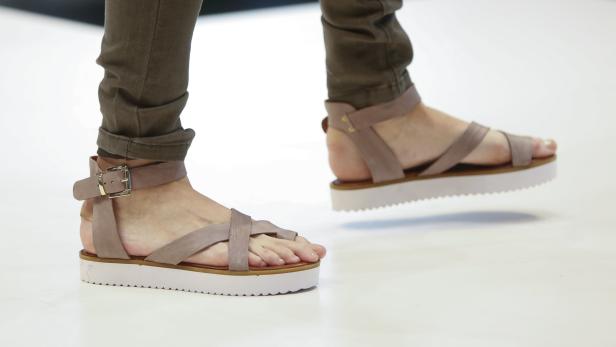 Nahaufnahme von Füßen in braunen Sandalen mit Plateausohle.