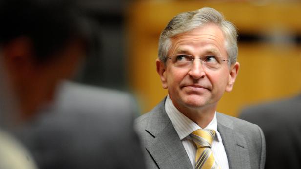 Ein Mann mit Brille, Anzug und gelber Krawatte blickt zur Seite.