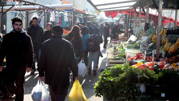 Menschen kaufen auf einem belebten Markt Obst und Gemüse ein.