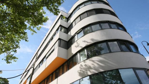 Ein modernes, weißes Gebäude mit abgerundeten Ecken unter blauem Himmel.