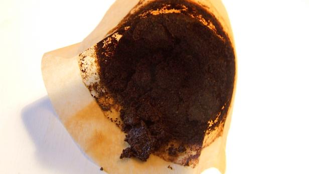 Ein benutzter Kaffeefilter mit Kaffeesatz auf einem weißen Untergrund.