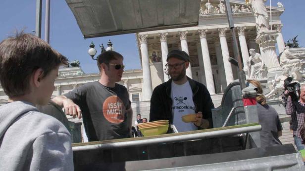 Zwei Männer stehen an einem Stand vor dem österreichischen Parlament in Wien.