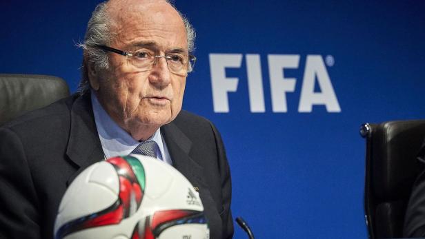 Sepp Blatter vor einem FIFA-Logo mit einem Fußball.