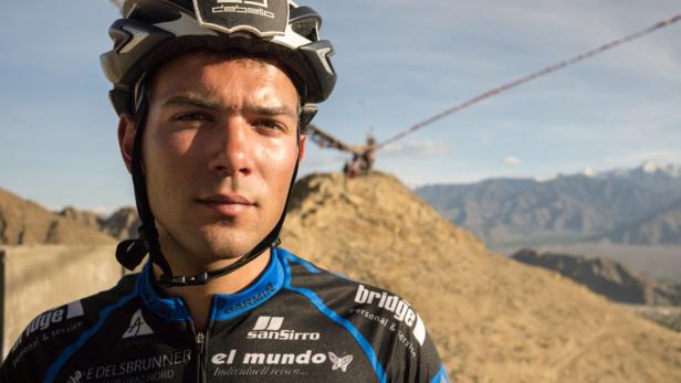 Ein Radfahrer mit Helm vor einer Berglandschaft.