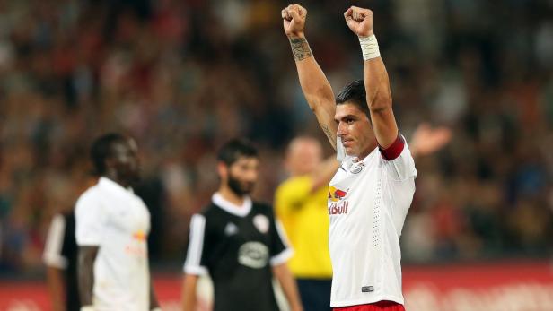 Ein Fußballspieler jubelt mit erhobenen Armen vor einer Zuschauermenge.