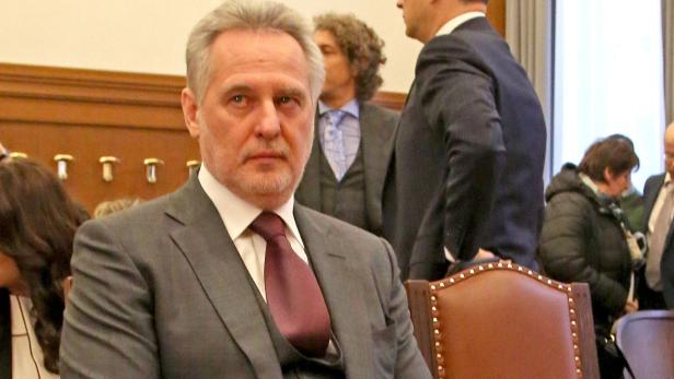 Ein Mann im Anzug sitzt während einer Veranstaltung.