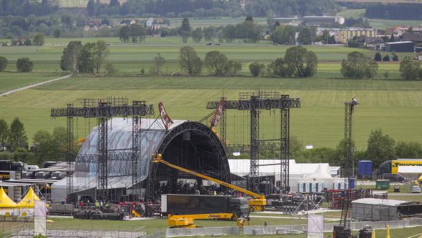 Auf einem Feld wird eine große Bühne für eine Veranstaltung aufgebaut.