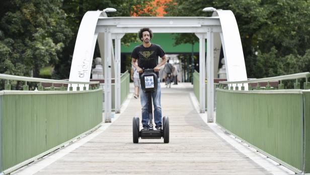 Ein Mann fährt mit einem Segway über eine Brücke.