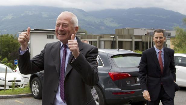 Zwei Männer in Anzügen stehen vor einem grauen Audi Q5 und lächeln.