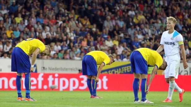 Drei Fußballspieler in gelben Trikots dehnen sich, während ein vierter in Weiß daneben steht.