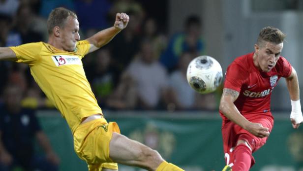 Zwei Fußballspieler kämpfen um den Ball während eines Spiels.