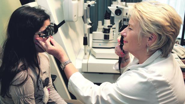 Eine junge Frau wird von einer Augenärztin untersucht.