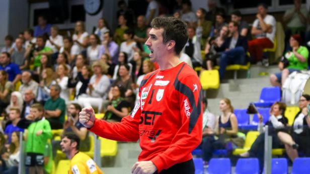 Ein Handballtorwart jubelt vor einer Zuschauertribüne.