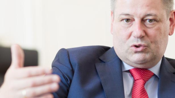 Ein Mann in Anzug und Krawatte gestikuliert während eines Gesprächs.