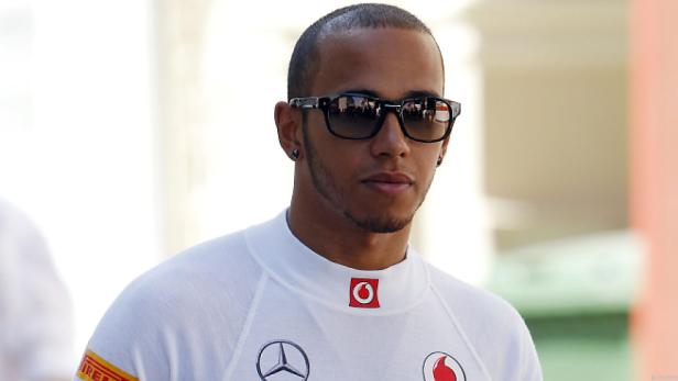 Lewis Hamilton mit Sonnenbrille vor einem hellen Hintergrund.