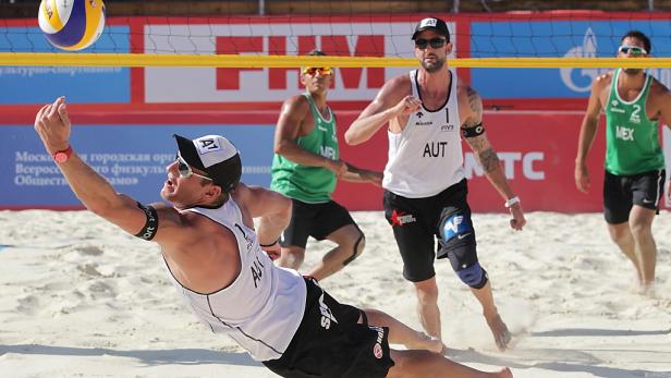Ein Beachvolleyballspieler aus Österreich schlägt den Ball über das Netz.