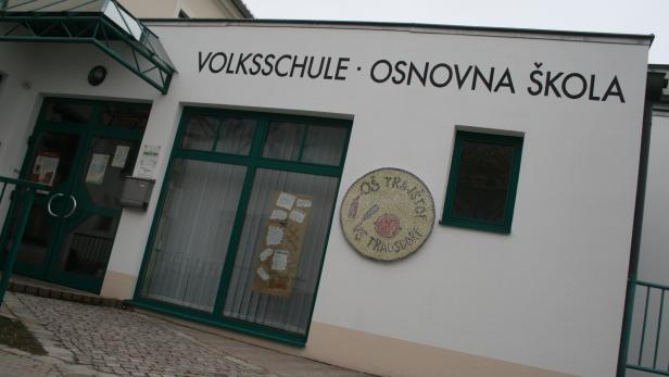 Weißes Gebäude, auf dem in deutsch und kroatisch Volksschule steht