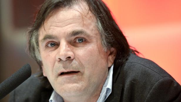 Ein Mann mit dunklen Haaren spricht in ein Mikrofon.