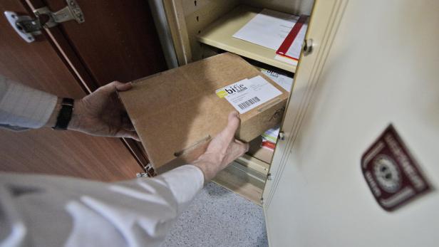 Eine Person verstaut einen Karton mit der Aufschrift „bifie“ in einem Schrank.