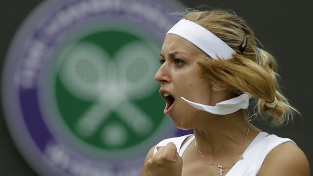 Eine Tennisspielerin jubelt mit geballter Faust vor dem Wimbledon-Logo.