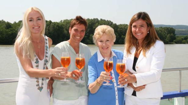 Vier Frauen stoßen auf einem Schiff mit Aperol Spritz an.