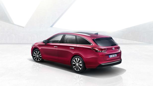 Ein roter Hyundai i30 Kombi vor einem hellen, modernen Gebäude.