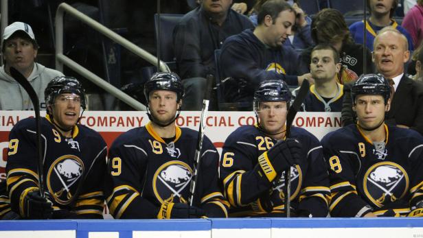 Vier Eishockeyspieler der Buffalo Sabres sitzen auf der Bank.
