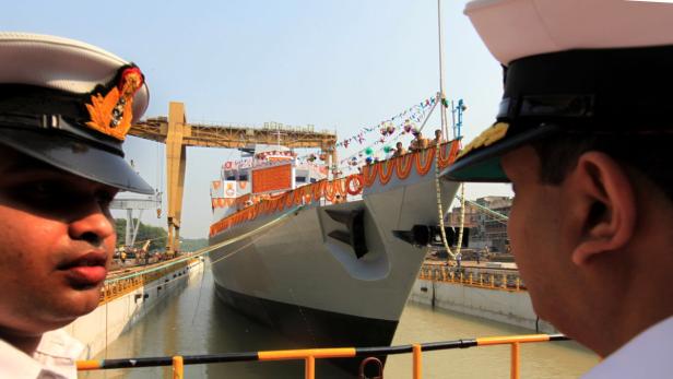 Zwei Marineoffiziere beobachten ein mit Girlanden geschmücktes Schiff im Trockendock.