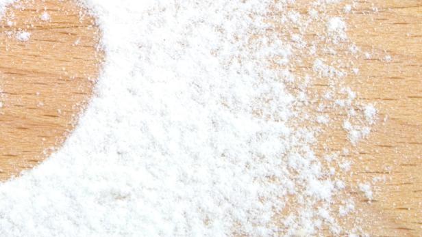Weißes Pulver, möglicherweise Mehl, auf einer Holzoberfläche.